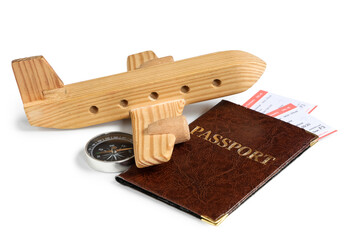 Passport with tickets, wooden plane and compass on white background