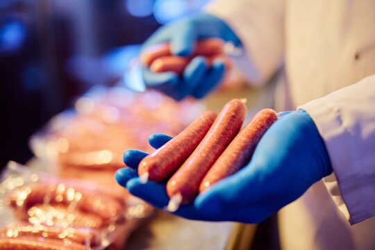 Gloves hold sausages in a factory