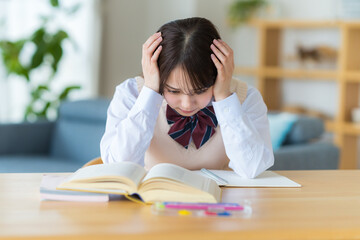 自宅で勉強中に悩む女子高生