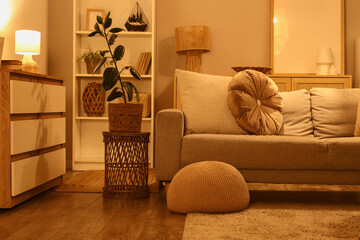 Cozy sofa, chest of drawers and glowing lamps in interior of living room