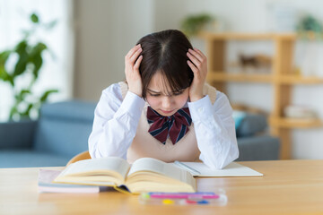 自宅で勉強中に悩む女子高生