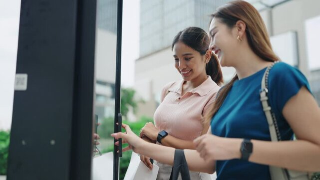 Women making contactless payment via touchscreen display at smart retail store