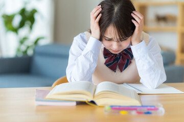自宅で勉強中に悩む女子高生