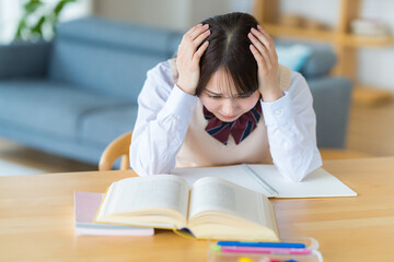 自宅で勉強中に悩む女子高生