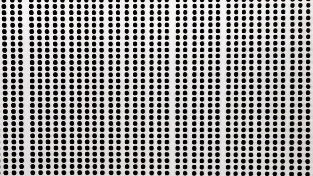 A perforated white panel features a repeating pattern of small, dark dots
