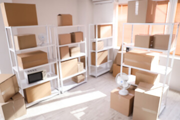 Blurred view of light warehouse with cardboard boxes on shelving units