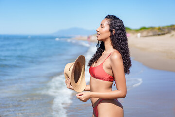 A Beautiful Woman is Relaxing and Enjoying a Joyful Day at the Beach while Wearing a Hat