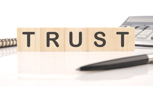 The concept word TRUST is assembled from wooden cubes. Investment based on trust concept