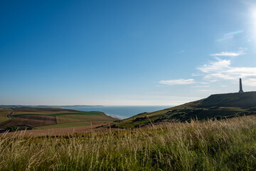 Cap Blanc-Nez, Escalles, Pas-de-Calais, Hauts-de-France, France, July 29th, 2025, A breathtaking coastal vista showcasing lush green hills alongside a historic tower beautifully situated by the sea