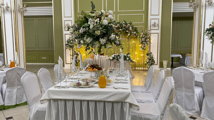 Elegant banquet table with floral centerpiece, fresh fruit, and drinks in luxurious banquet hall....