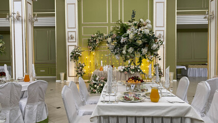 Elegant banquet hall with a beautifully decorated table featuring floral arrangements, crystal glasses, and a serene atmosphere. Perfect setting for a wedding, celebration, or special event