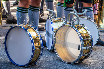 Festival parade features musicians in traditional attire playing drums along a lively street in a...