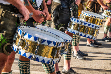 Festival parade features musicians in traditional attire playing drums along a lively street in a...