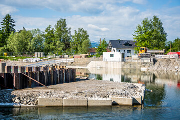 Construction site along a riverbank featuring portable structures and protective vegetation in a...