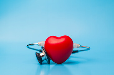 Red heart shape exercise ball with doctor physician's stethoscope on blue background, hospital life insurance concept, world heart health day. doctor day