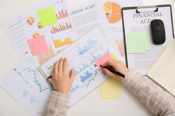 Woman with pen and business charts working at table in office, closeup