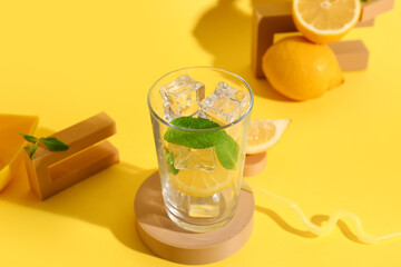 Fototapeta premium Composition with glass of lemonade, fresh sliced lemons and mint on yellow background