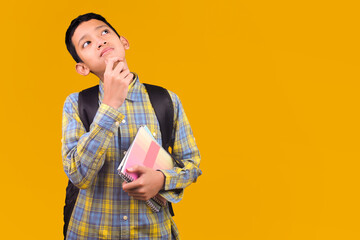 Pensive Young Asian Student Holding Notebook And Looking Up Thoughtfully With Hand On Chin