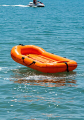 Fototapeta premium Orange life raft on the water, perfect for summer activities.