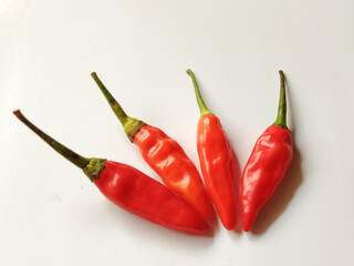 A striking close-up of hot red chilies, isolated on a crisp white background, emphasizing their...