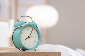Retro alarm clock on bedside table in bedroom, closeup