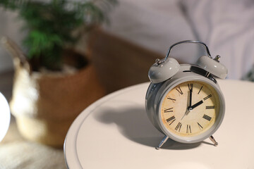 Retro alarm clock on bedside table in bedroom, closeup