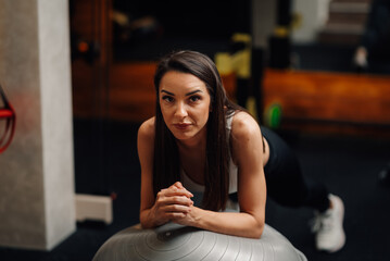 Fitness woman performing plank exercise on swiss ball in gym