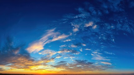 Fototapeta premium Sweeping Blue Sky Panorama with Scattered Clouds and Vibrant Sunset Hues Over Horizon