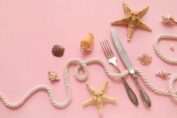 Beautiful composition with silver cutlery, rope, seashells and starfishes on pink background