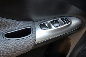 Window control buttons in modern car. Car interior details of door handle with windows controls and...