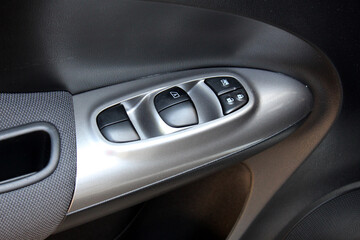 Naklejka premium Window control buttons close up in modern car. Car interior details of door handle with windows controls. Grey Car Door trim. Modern grey car interior.