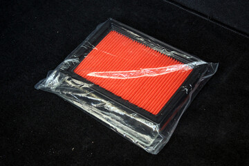 New orange car air filter in package. Auto part car air filter lying on seat. Air filter...