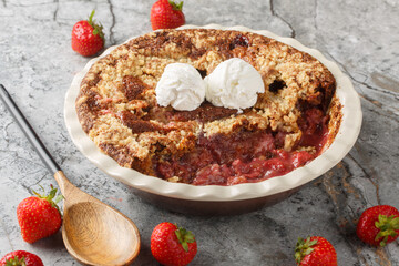 Strawberry cobbler pie with ice cream close-up in baking dish on table. Horizontal