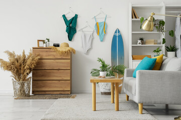 Interior of living room with sofa, surfboard and swimsuits