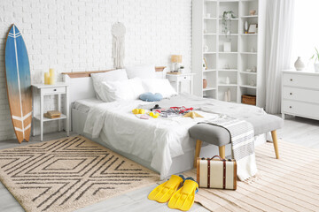 Interior of bedroom with beach accessories, surfboard and tables