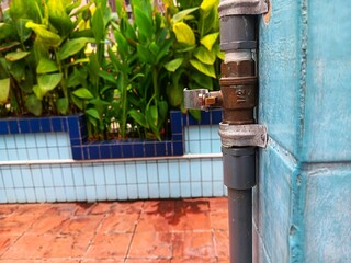 Outdoor showers valve or faucet mounted on blue wall in the swimming pool.