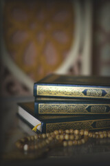 Holy quran and prayer beads on dark background