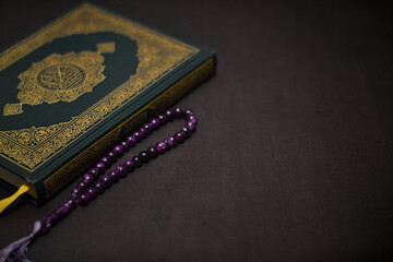 Holy quran and prayer beads on dark background