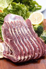 Beef ribs with lemon, onion and lettuce on a wooden cutting board