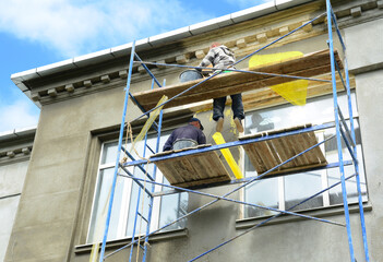 Builders plastering the facade of a house before painting the wall