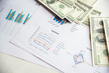 Office desk money bank note financial report business chart graph on wood table. Flat lay money stack business stuff on office desk. No people spreadsheet graph chart mockup on business workspace