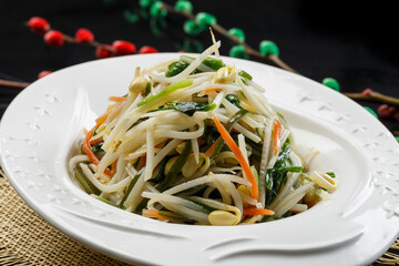White porcelain plate with spinach, carrot and bean sprouts