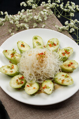 Steamed cucumber with vermicelli and garlic paste on a white porcelain plate