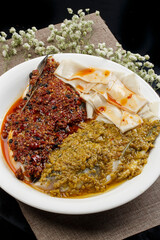 Steamed fish head with double peppers on a white porcelain plate