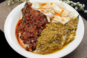 Steamed fish head with double peppers on a white porcelain plate