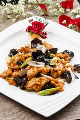 Braised pork tenderloin with scallion and wood ear mushrooms on a white porcelain plate