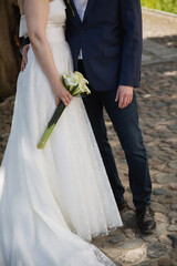 Outfits of a bride in white dress and a groom in blue suit standing outdoors 