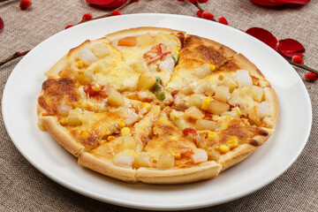 Homemade corn and ham pizza on a white porcelain plate