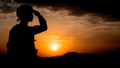 Silhouette of a person saluting at sunset.