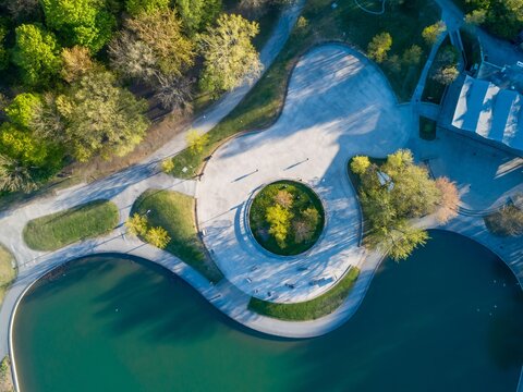 Aerial view of people enjoying a sunny day at a park with a pond and walking paths in the United States. The park offers a space for recreation and relaxation. Beaver Lake, Montreal, Quebec, Canada